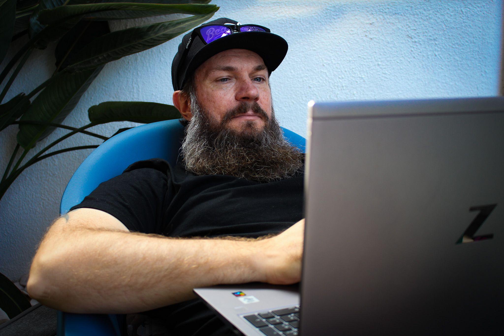 Systemutvecklare på Majako sitter i en blå fåtölj utomhus med sin dator i knät.