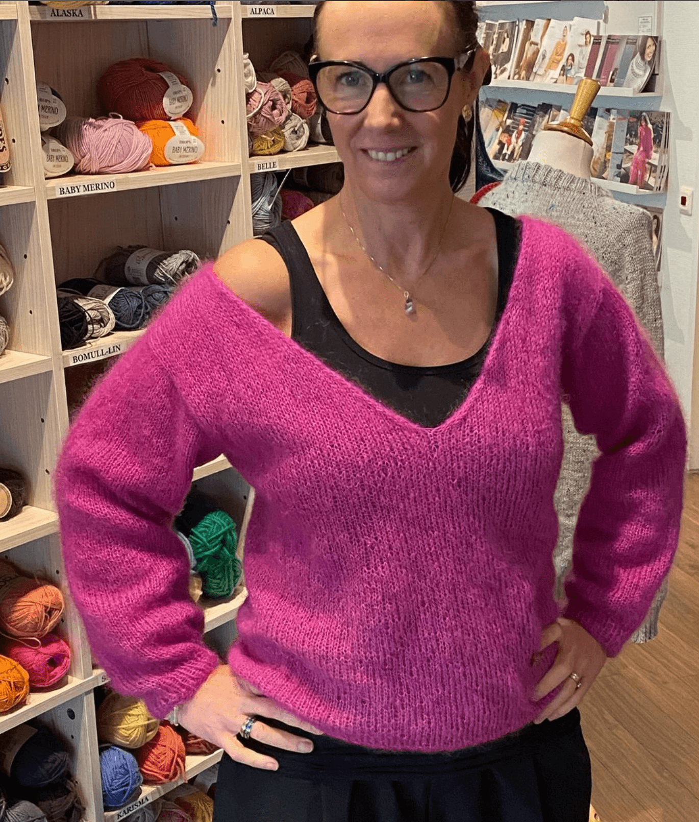 Kvinna med svarta glasögon och rosa stickad tröja.