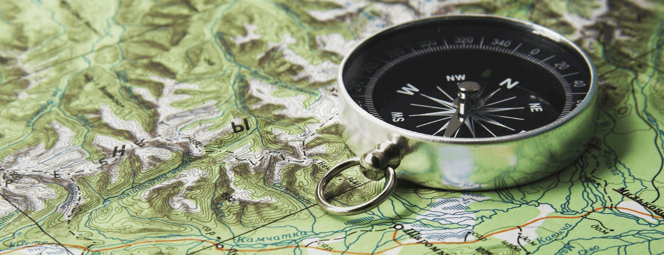 Silvrig kompass på en utvikt karta.